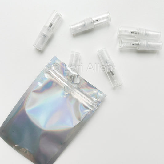 Set of clear plastic vials with a holographic pouch on a white background
